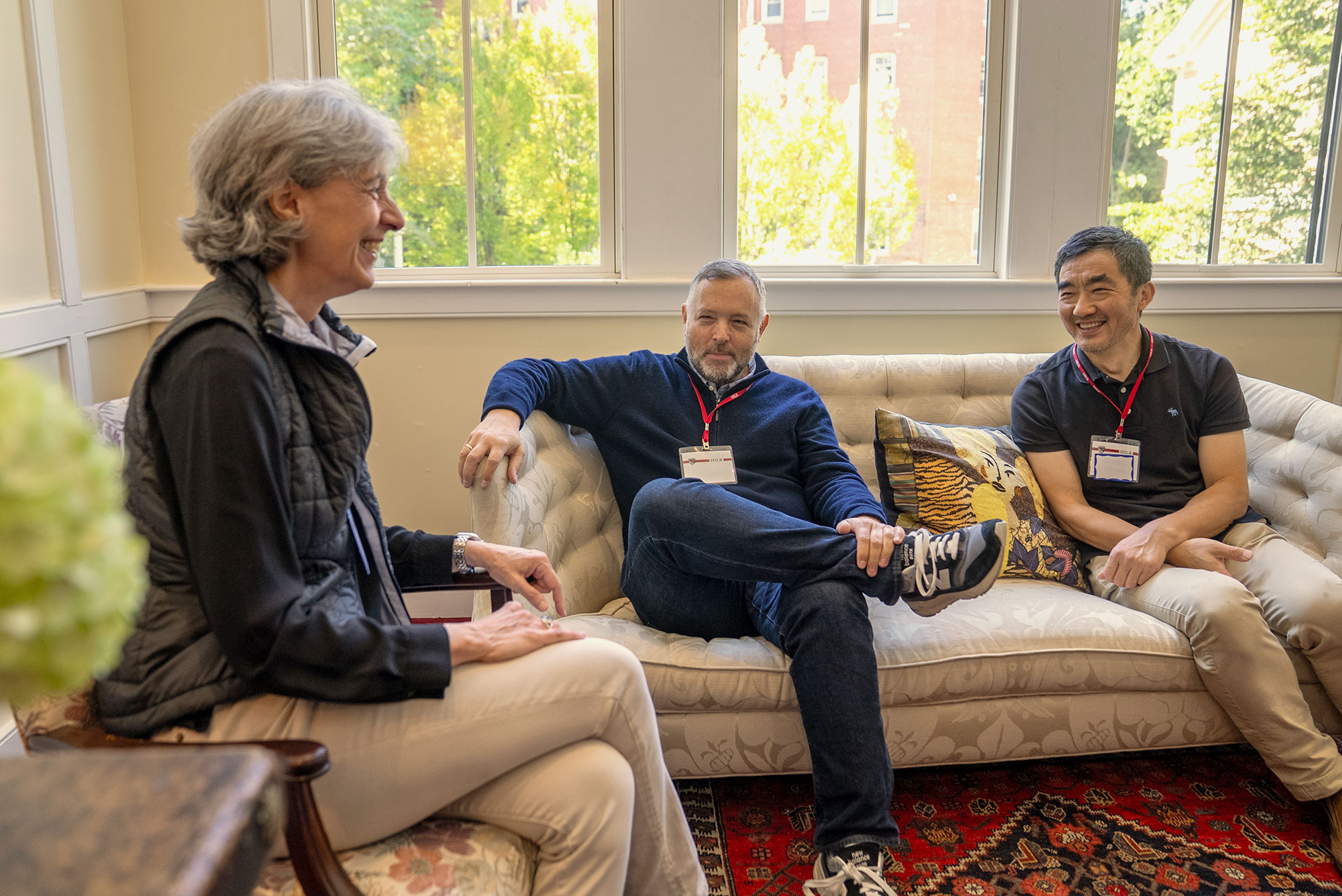 Three Harvard Institute for Learning in Retirement members talk while sitting on a couch.