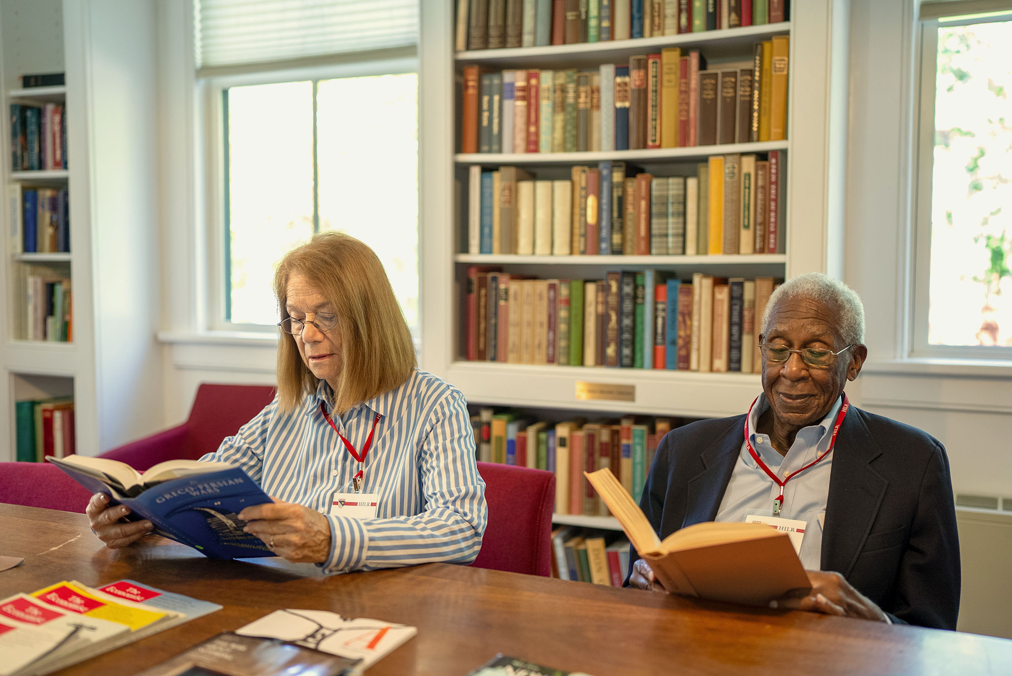 Two Harvard Institute for Learning in Retirement members read in the library.